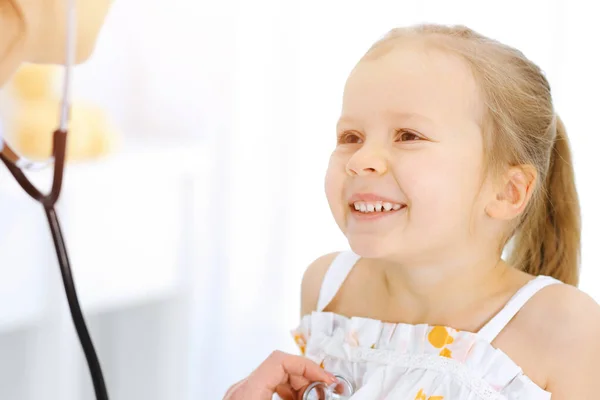 Docteur examinant une petite fille par stéthoscope. Heureux enfant patient souriant à l'inspection médicale habituelle. Médecine et concepts de santé — Photo