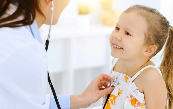 Arzt untersucht ein kleines Mädchen per Stethoskop. Glücklich lächelnder Kinderpatient bei der üblichen ärztlichen Untersuchung. Medizin- und Gesundheitskonzepte — Stockfoto