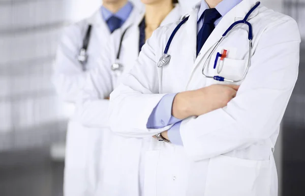 Group of modern doctors standing as a team with crossed arms and stethoscopes in hospital office. Physicians ready to examine and help patients. Medical help, insurance in health care, best desease — Stock Photo, Image