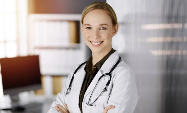 Allegro sorridente medico donna in piedi in clinica soleggiata. Ritratto di donna medico amichevole. Servizio medico perfetto in ospedale. Concetto di medicina — Foto Stock