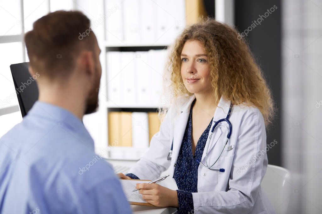 Female doctor and man-patient discussing current health examination while sitting in clinic. Perfect medical service and medicine concept