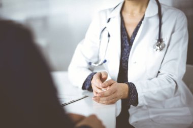 Bilinmeyen kadın-doktor, klinikteki dolapta birlikte otururken hastasıyla teşhisi hakkında konuşuyor. İşyerindeki doktor, yakın plan. Mükemmel bir tıbbi hizmet.