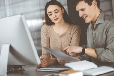 Yeşil gömlekli genç işadamı ve programcı ve bayan meslektaşı modern bir ofiste masada birlikte otururken yeni iş planlarını tartışıyorlar. Kadınlara odaklan. Başarılı olma kavramı