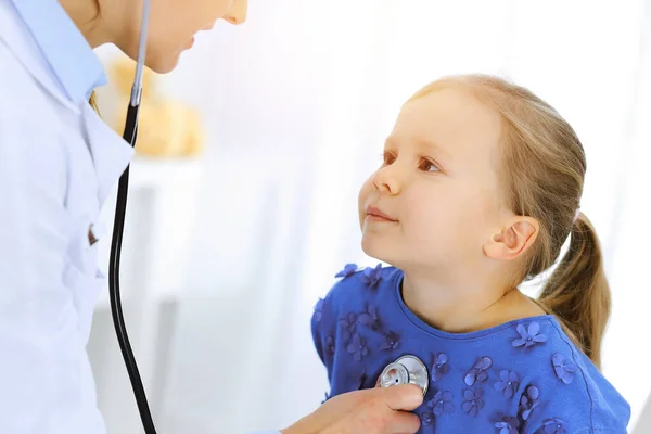 Dokter die een klein meisje onderzoekt met stethoscoop. Gelukkige glimlachende kindpatiënt bij gebruikelijke medische inspectie. Begrippen geneeskunde en gezondheidszorg — Stockfoto