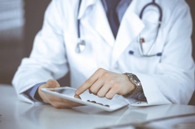 Bilinmeyen erkek doktor klinikteki tablet bilgisayarla yakın planda çalışıyor. İşteki genç doktor. Mükemmel sağlık hizmeti, tıp konsepti