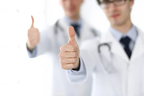 Zwei männliche Ärzte stehen als Team und zeigen Daumen nach oben als Symbol für den besten Service für Patienten in der Klinik. Medizin und Gesundheitsfürsorge — Stockfoto