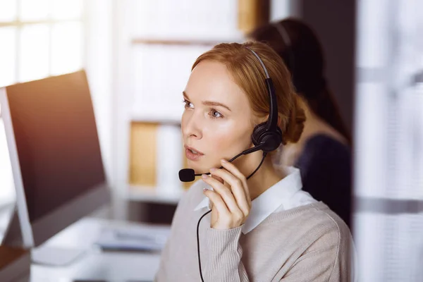 Femme d'affaires parlant par casque dans le bureau. Centre d'appels et divers groupes de personnes en affaires — Photo