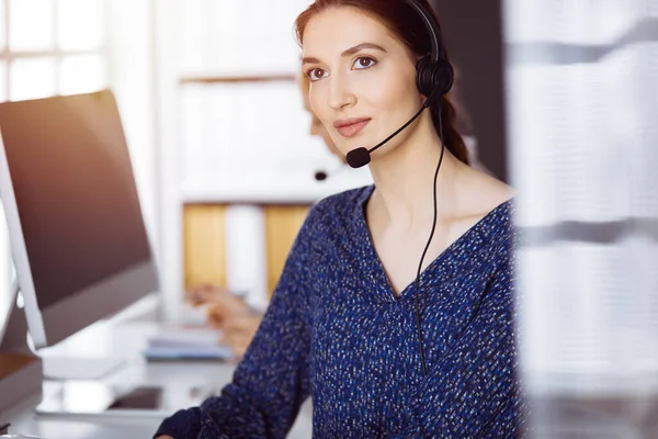 Empresaria latinoamericana hablando por auriculares en la oficina. Centro de llamadas y grupo de personas diversas en los negocios — Foto de Stock