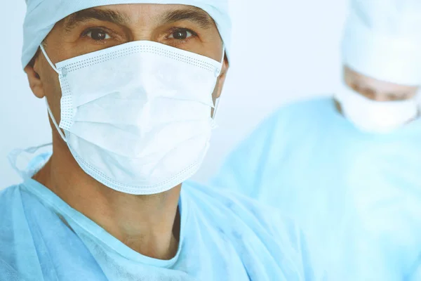 Um cirurgião do sexo masculino, um grupo de cirurgiões está a operar em segundo plano. Conceito de saúde — Fotografia de Stock