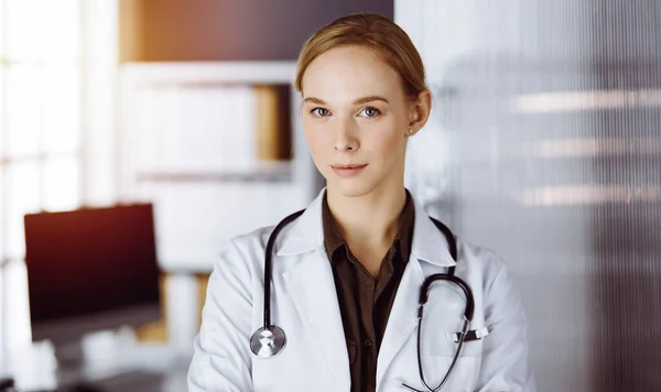 Allegro sorridente medico donna in piedi in clinica. Ritratto di donna medico amichevole. Servizio medico in ospedale. Concetto di medicina — Foto Stock