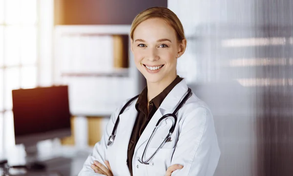 Allegro sorridente medico donna in piedi in clinica. Ritratto di donna medico amichevole. Servizio medico in ospedale. Concetto di medicina — Foto Stock