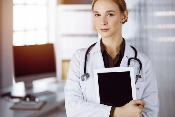 Allegro sorridente medico femminile utilizzando appunti in clinica. Ritratto di donna medico amichevole al lavoro. Servizio medico in ospedale. Concetto di medicina — Foto Stock