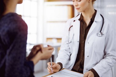 Gülümseyen neşeli kadın doktor ve hasta kadın klinikte otururken sağlık muayenesini tartışıyorlar. Hastanede tıbbi hizmet. Tıp konsepti