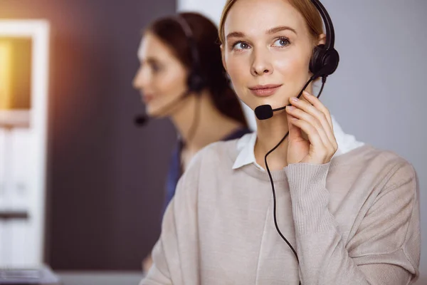 Femme d'affaires parlant par casque dans le bureau. Centre d'appels et divers groupes de personnes en affaires — Photo