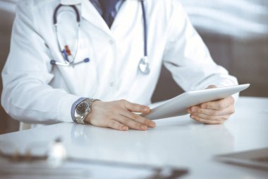 Bilinmeyen erkek doktor klinikteki tablet bilgisayarla yakın planda çalışıyor. İşteki genç doktor. Mükemmel sağlık hizmeti, tıp konsepti