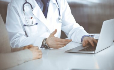 Bilinmeyen erkek doktor ve hasta kadın klinikte oturup dizüstü bilgisayar kullanırken bir şeyler tartışıyorlar. Hastanedeki en iyi sağlık hizmeti, ilaç, salgın durdurma.