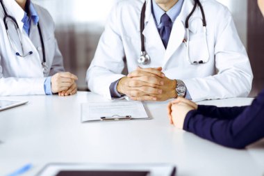 Meçhul erkek doktor modern klinikte otururken hasta kadını dinliyor. Mükemmel tıbbi servis, Coronavirus salgını sırasında ilaç konsepti. Covid 2019