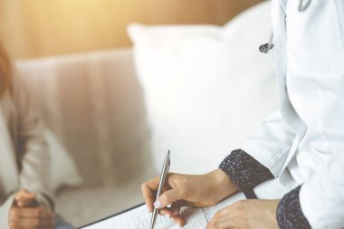 Kadın-doktor ve hasta yakın plan çekimleri. İçeride otururken sağlık muayenesini tartışıyorlar. Coronavirus salgını ve kendini izolasyon karantinası sırasında evde kal. Covid 2019