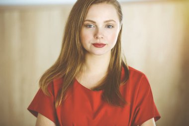 Zeki, kendinden emin, gülümseyen Avrupalı bir kadının resmi. Kollarını kavuşturmuş evde bekliyor.