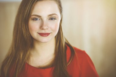 Zeki, kendinden emin, gülümseyen Avrupalı bir kadının resmi. Kollarını kavuşturmuş evde bekliyor.