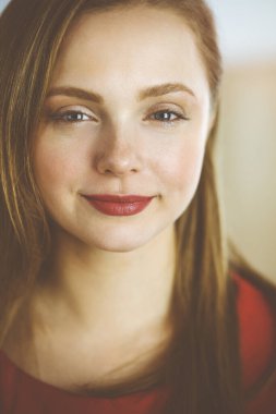 Zeki, kendinden emin, gülümseyen Avrupalı bir kadının resmi. Kollarını kavuşturmuş evde bekliyor.