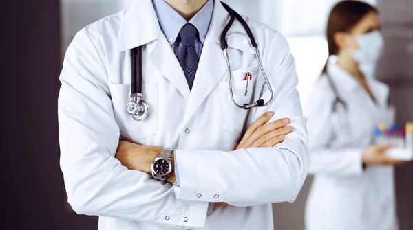 Unknown male doctor in protective mask standing with arms crossed in clinic. Medicine concept during Coronavirus pandemic. Covid 2019 — Stock Photo, Image