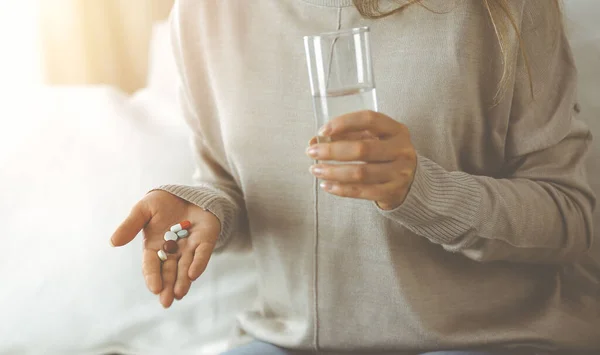 Närbild kvinna håller piller tid att ta mediciner, bota mot huvudvärk. Medicinskt koncept under självisolering och Coronavirus pandemi — Stockfoto