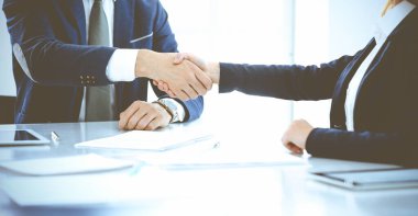 İş adamları ya da avukatlar mavi tonlu ofiste toplantıyı bitirirken el sıkışıyorlar. Müzakere ve tokalaşma kavramlarında başarı