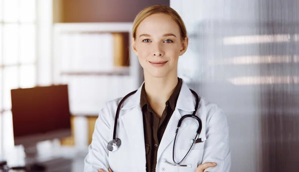 Allegro sorridente medico donna in piedi in clinica. Ritratto di donna medico amichevole. Servizio medico in ospedale. Concetto di medicina — Foto Stock