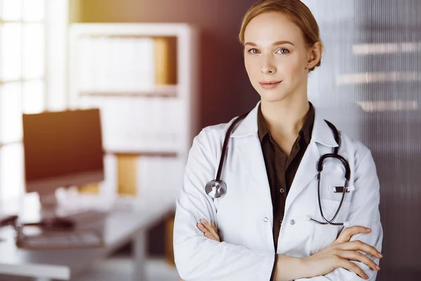 Allegro sorridente medico donna in piedi in clinica. Ritratto di donna medico amichevole. Servizio medico in ospedale. Concetto di medicina — Foto Stock