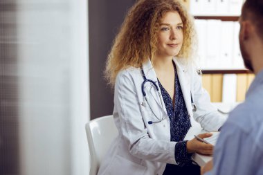 Kadın doktor ve hasta güneşli klinikte otururken sağlık muayenesini tartışıyorlar. Tıp konsepti