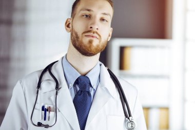 Güneşli klinikte duran dost canlısı sakallı doktor. Hekim portresi. Tıp konsepti