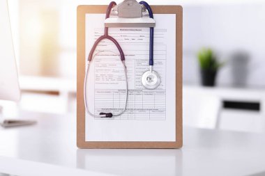 Üzerinde ilaç geçmişi olan steteskop ve dosya güneşli doktorların çalıştığı yerde masada. Tıp konsepti