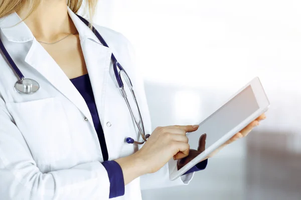 신원을 알 수없는 여성 과 의사가 밝은 진료소 캐비닛에 서 있는 동안 손에 태블릿 컴퓨터를 들고 있다. 여성 의사가 일하고 있고, 클로즈업중입니다. 병원에서의 완벽 한 의료 서비스. 의학적 개념 — 스톡 사진