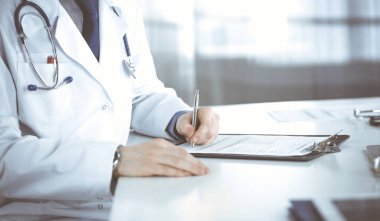 Bilinmeyen erkek doktor, klinikteki ilaç geçmişi kayıtlarıyla birlikte yakın planda oturuyor. İşteki genç doktor. Mükemmel sağlık hizmeti, tıp konsepti