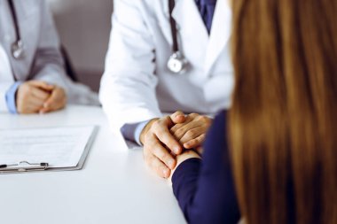 Bilinmeyen erkek-doktor, kadın hastasına güvence veriyor, yakın plan. İki doktor kadınlara danışmanlık yapıyor ve tavsiyelerde bulunuyor. Mükemmel tıbbi hizmet, Coronavirus salgını sırasında tıpta empati. Kapalı