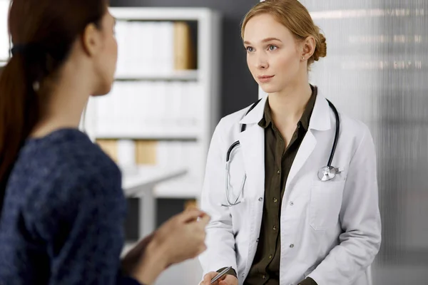 Femme souriante amicale médecin et patiente discutant de l'examen de santé en cours alors qu'elle était assise à la clinique. Service médical parfait à l'hôpital. Concept de médecine — Photo