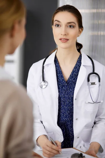 Amigável sorridente médico e paciente mulher discutindo exame de saúde atual enquanto sentado na clínica. Serviço médico perfeito no hospital. Conceito de medicina — Fotografia de Stock