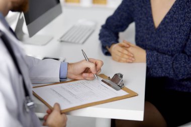 Bilinmeyen sakallı doktor ve hasta kadın güneşli klinikte otururken sağlık muayenesini tartışıyorlar. Yakın plan. Tıp konsepti
