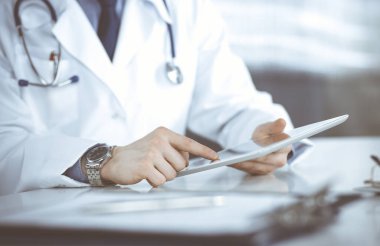 Bilinmeyen erkek doktor klinikteki tablet bilgisayarla yakın planda çalışıyor. İşteki genç doktor. Mükemmel sağlık hizmeti, tıp konsepti