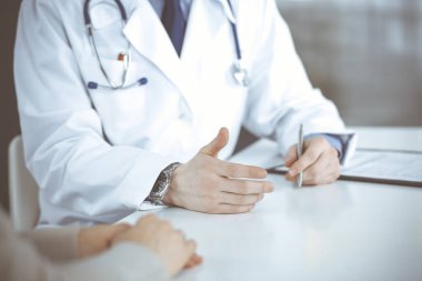 Bilinmeyen erkek doktor ve hasta kadın klinikte oturup dosya kullanırken bir şey tartışıyorlar. Hastanedeki en iyi sağlık hizmeti, ilaç, salgın durdurma.