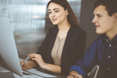 Çalışma masasında birlikte otururken iş yerindeki genç ve dost canlısı iş adamları. Kadınlara odaklan. Modern bir ofiste vesikalık ya da iş portresi