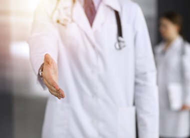 Bilinmeyen bir adam-doktor ayakta duruyor ve modern klinikte yardım eli uzatıyor. Kadın meslektaşının doktor geçmişinde acelesi var. Tıp konsepti