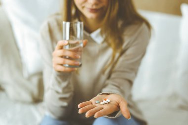 Kapalı çekim kadın ilaç almak için zaman tutuyor, baş ağrısı için tedavi, yüksek tansiyon veya kolesterol seviyesinde ağrı kesici ilaçlar. Coronavirus salgını ve kendi kendine olan konseptinde kal.