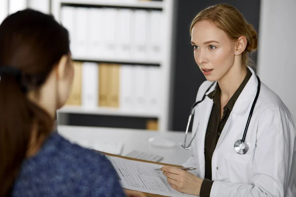 Femme souriante amicale médecin et patiente discutant de l'examen de santé en cours alors qu'elle était assise à la clinique. Service médical parfait à l'hôpital. Concept de médecine — Photo