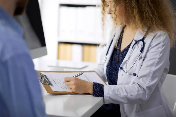 Médica e paciente do sexo masculino discutindo o exame de saúde atual enquanto sentado na clínica, close-up — Fotografia de Stock