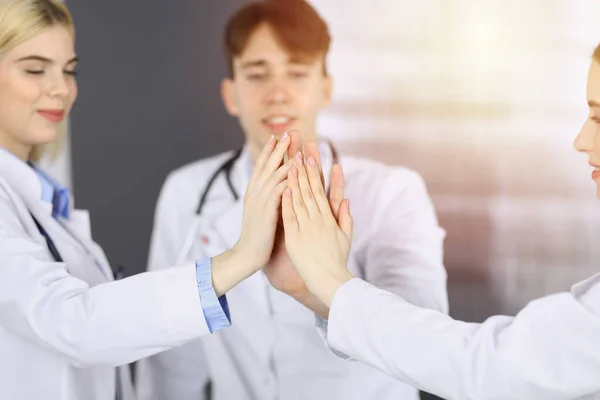 Skupina moderních lékařů se drží za ruce a dává si pět jako znamení silné týmové práce a jsou připraveni pomáhat pacientům. Koronavirus měření a medicína koncept — Stock fotografie