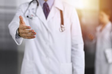 Bilinmeyen bir adam-doktor ayakta duruyor ve modern klinikte yardım eli uzatıyor. Kadın meslektaşının doktor geçmişinde acelesi var. Tıp konsepti