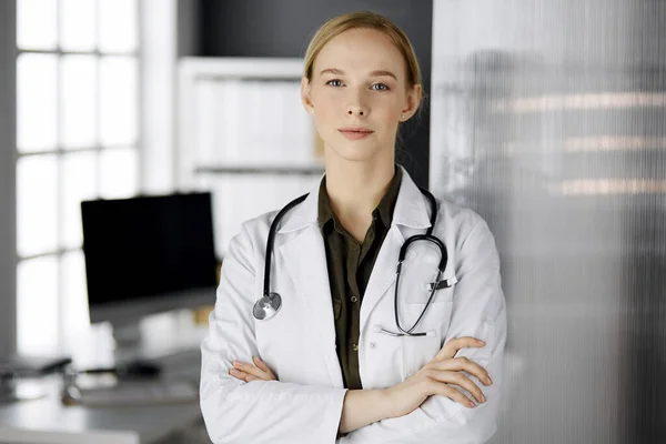 Amichevole dottoressa sorridente in piedi in clinica. Ritratto di donna medico amichevole. Servizio medico perfetto in ospedale — Foto Stock