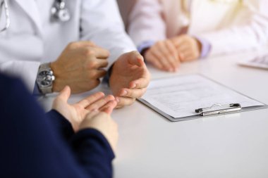 Bilinmeyen erkek doktor güneşli klinikte otururken hasta kadını dinliyor. Coronavirus salgını sırasında ilaç konsepti. Covid 2019
